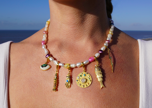 Close-up of a person wearing a colorful necklace with charms against a blue sky background