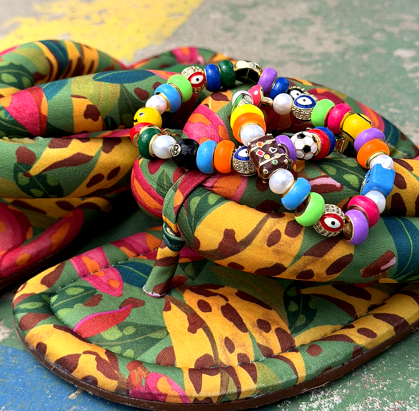 Colorful flip-flops with beaded bracelets on a textured surface