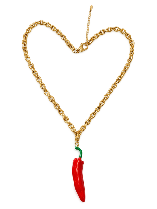 A gold chain necklace arranged in a heart shape, featuring a dangling red chili pepper charm with a green stem, shown on a plain white background.