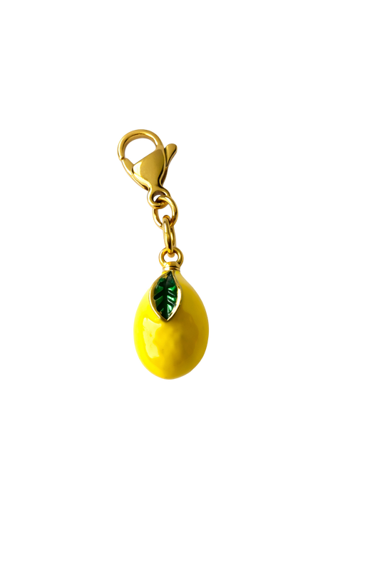 Yellow lemon-shaped charm with a green leaf on a white background