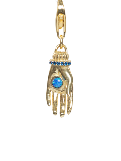 Gold charm shaped like a hand with a blue gem on a white background