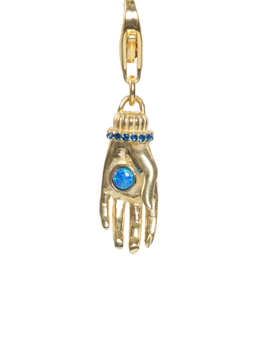 Gold charm shaped like a hand with a blue gem on a white background