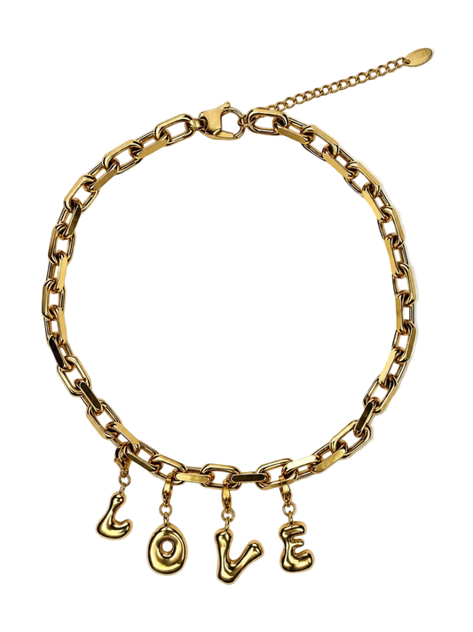 A gold-tone chain MILLIE MADNESS necklace with four dangling letter charms spelling out 'LOVE', displayed on a clean white background.
