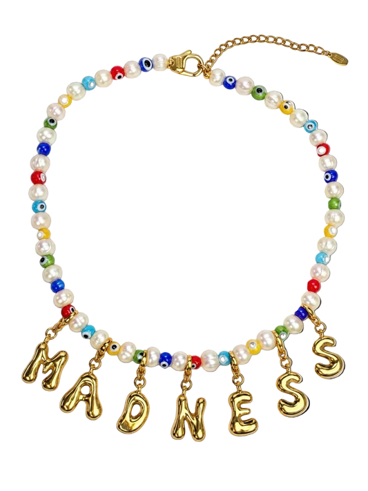 A beaded statement necklace featuring white faux pearls, colorful evil eye beads, and gold letter charms spelling MILLIE MADNESS 'MADNESS' on a white background.