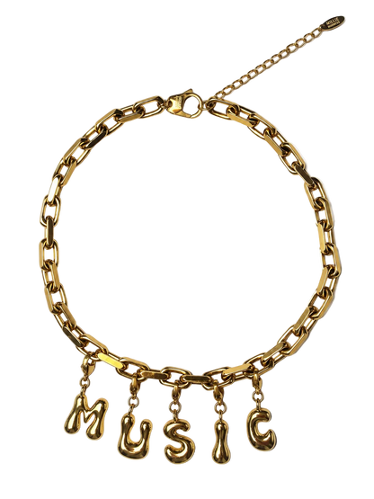 A gold-tone MILLIE MADNESS chain necklace with dangling letter charms spelling out 'MUSIC' in a bold, chunky link style, shown on a plain white background.