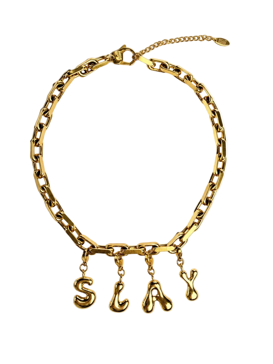 A gold-tone chain millie madness necklace with dangling lowercase letters spelling 'SLAY', photographed on a clean white background.