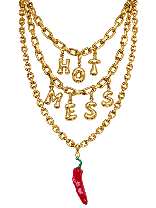 A gold multi-layered millie madness chain necklace featuring dangling letters spelling 'HOT MESS' and a red chili pepper charm at the bottom, shown on a plain white background.