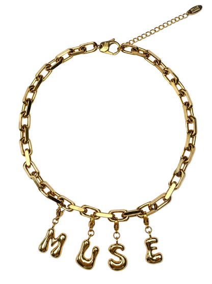 A gold-tone millie madness chain necklace with dangling letter charms spelling 'MUSE' on a plain white background.