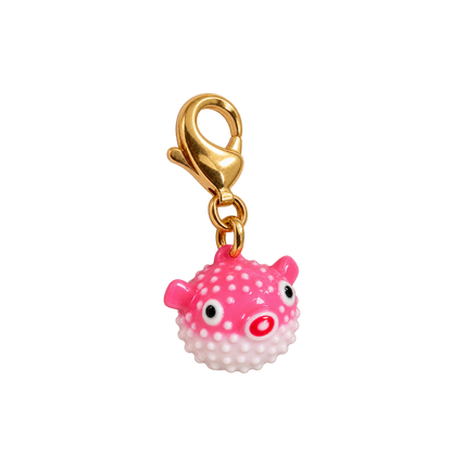 A pink puffer fish charm with white polka dots, black eyes, and a red nose, attached to a gold lobster clasp, shown on a plain white background.